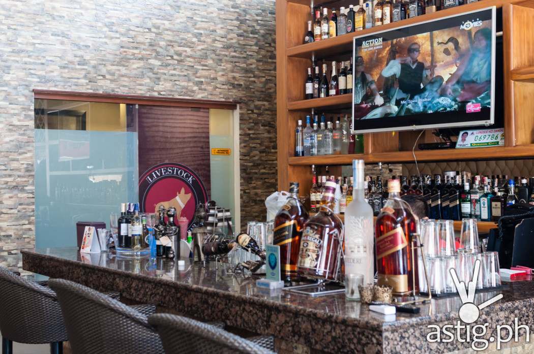 The bar has a television set surrounded by bottles of alcohol