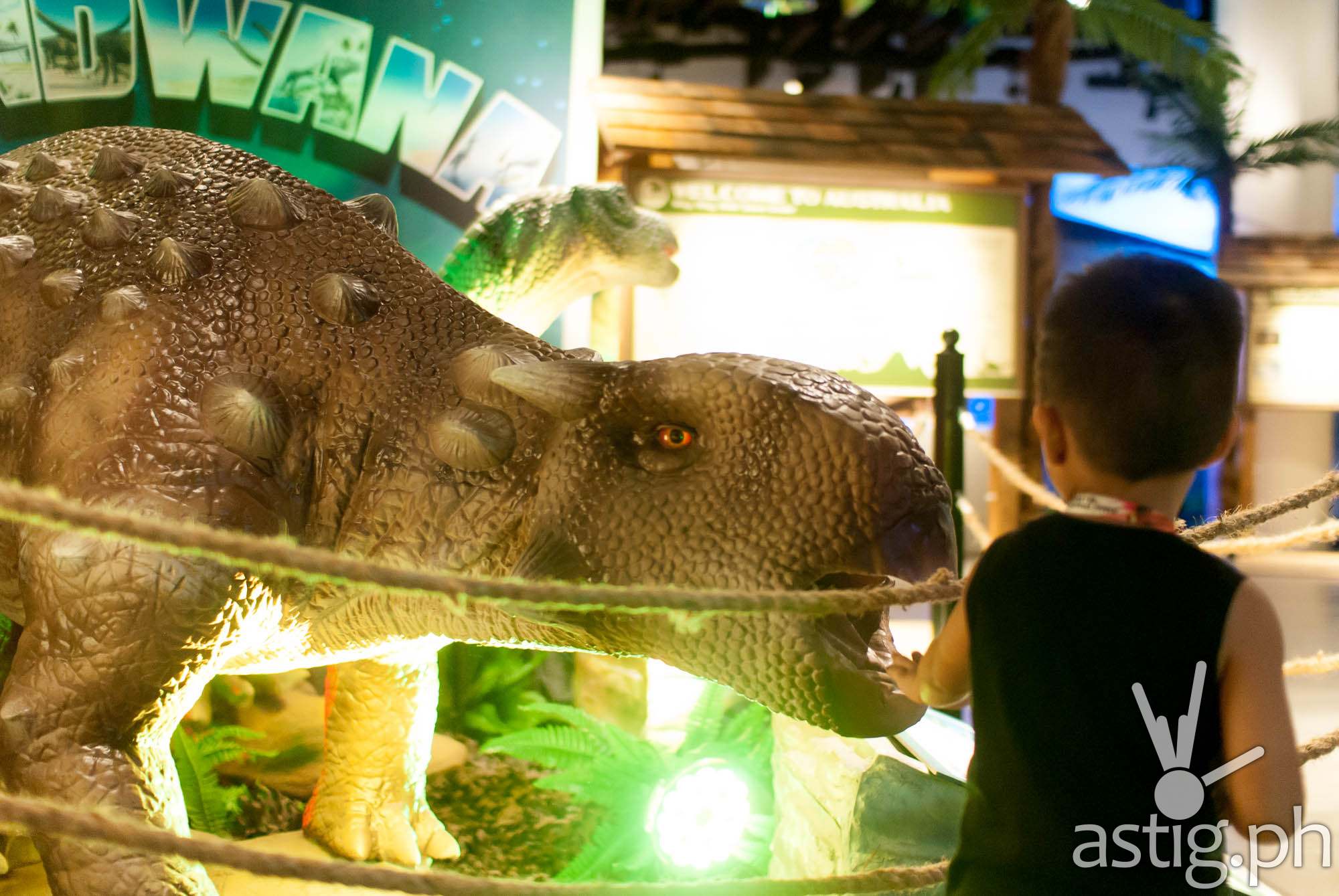 Kid touching animatronic dinosaur -Dinosaurs Around The World exhibit - Mind Museum BGC