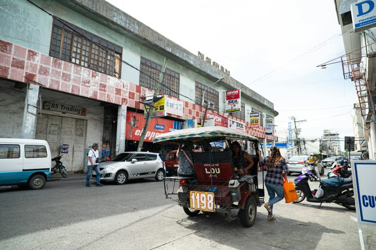 Tuk-tuk and people on a busy city street.